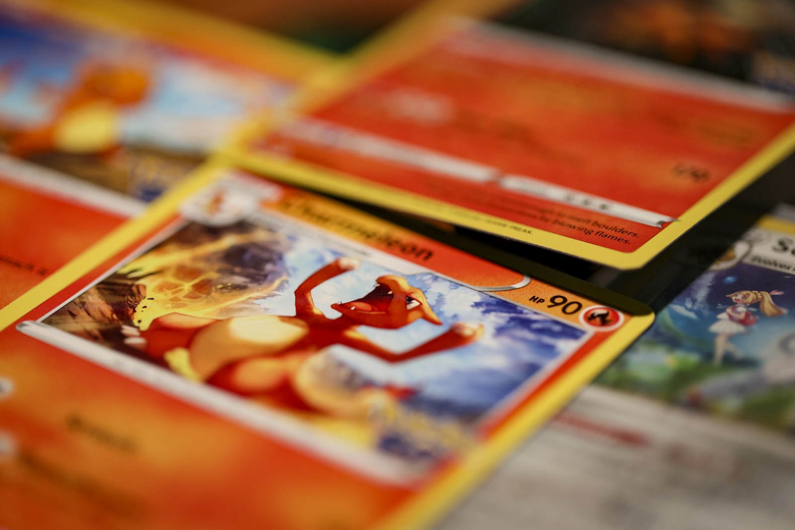Close-up photograph of overlapping English Pokémon cards, with a Charizard card in the foreground.